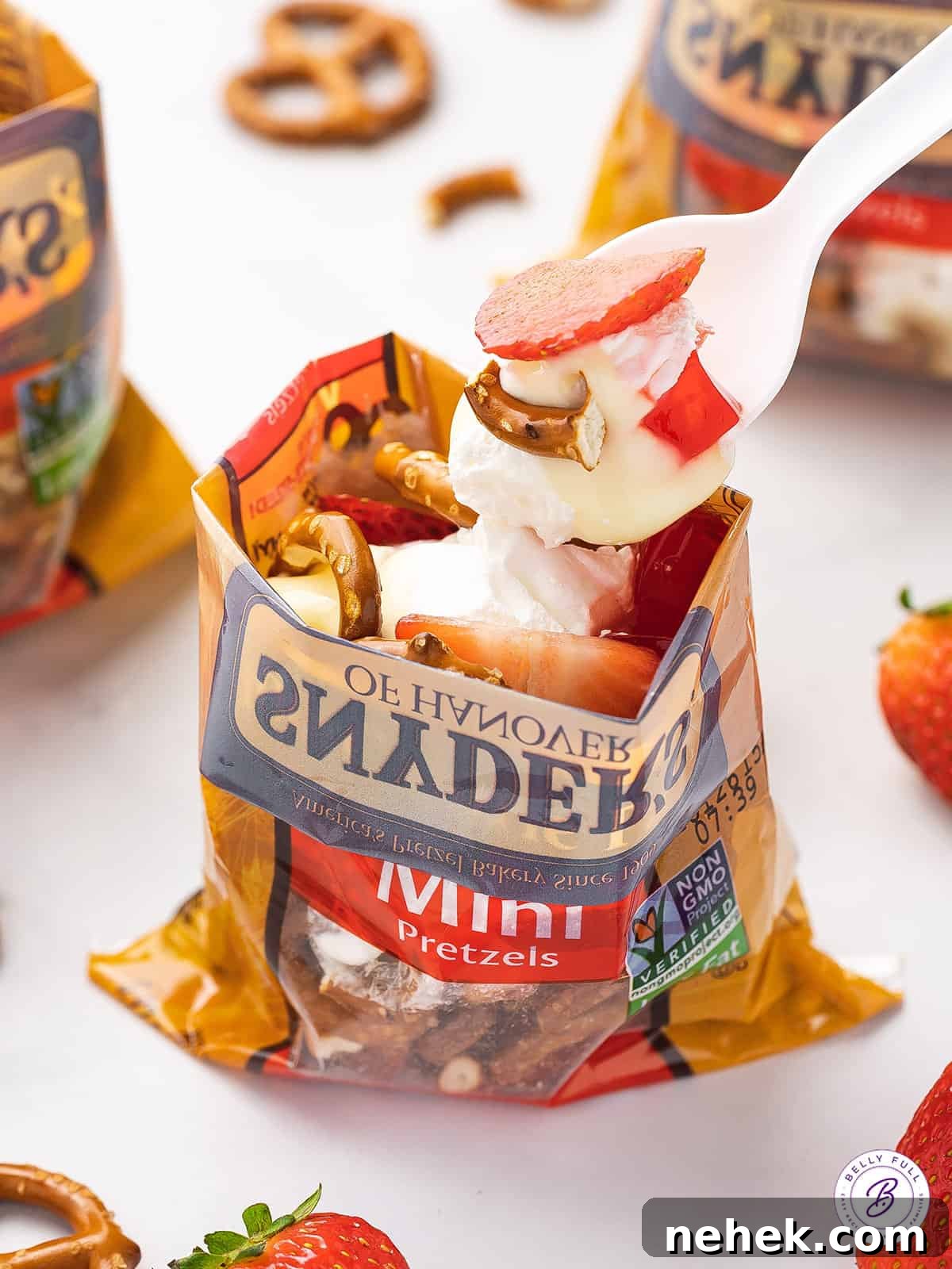 Made with cheesecake pudding, strawberry jello, whipped cream, and pretzels, this Walking Strawberry Pretzel Salad is a fun, portable dessert. A spoon serving from a walking strawberry pretzel salad